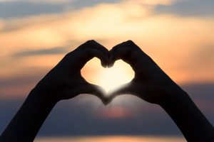 Hands shaped into a heart with sunset in background